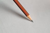 Detailed close-up of a wooden pencil resting on white paper, perfect for educational themes.