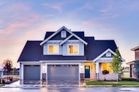 Beautiful two-story house with illuminated windows and garage at dusk.