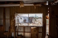 Explore an eerie view through a broken window of an abandoned structure in Arizona's desert landscape.