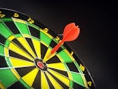 Close-up of a dart successfully hitting the bullseye on a bright dartboard, signifying victory.