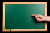 Green chalkboard framed in wood with a hand pointing, isolated on black. Ideal for educational themes.