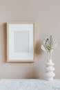 Elegant minimalist interior with a wooden frame and sculptural vase on a marble surface.