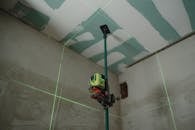 A laser level tool in action at an indoor construction site with marked walls.