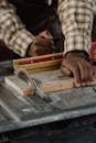 Close-up of a carpenter using a table saw to cut a wooden plank in a workshop.