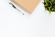 Minimalist stationery setup with a spiral notebook and pen on a clean white desk.