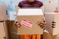 A person holding a cardboard box labeled 'Fragile' during a moving process indoors.